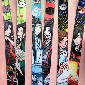 Może przedstawiać: Pięć kolorowych sznurków z nadrukowanymi postaciami w stylu anime. Sznurki przedstawiają różne postacie i wzory, w tym postać z mieczem, postać z wachlarzem, postać z chmurą, postać z czerwoną wstążką i postać z niebieskim blaskiem.