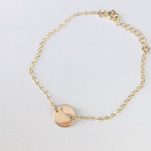 Peut inclure: Un bracelet en chaîne dorée avec un petit charme rond en or.