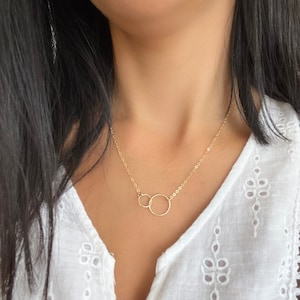 May include: A gold chain necklace with two interlocking circles as a pendant.
