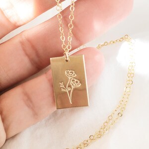 Peut inclure: Un collier en or avec un pendentif rectangulaire orné d'un motif floral délicat. Le pendentif est gravé de deux fleurs stylisées et d'une tige.