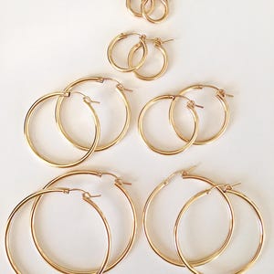 Peut inclure: Ensemble de six boucles d'oreilles créoles dorées de différentes tailles. Les boucles d'oreilles sont toutes en métal lisse et brillant.