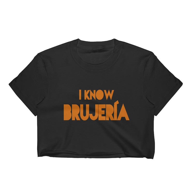 Puede incluir: Camiseta negra recortada con el texto "I know BRUJERIA" en naranja.