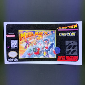 Op de afbeelding: Een Mega Man X3 Super Nintendo game cartridge label. Het label toont een levendige illustratie van de personages van het spel in actie, met de titeltekst in vette, kleurrijke letters. De Capcom- en Nintendo-logo's zijn ook zichtbaar.