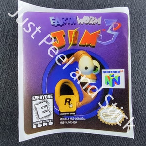 May include: A purple and blue video game cartridge for the Nintendo 64 console. The game is Earthworm Jim 3D. The ESRB rating is Everyone. The game is rated R by Rockstar Games. The cartridge has a Nintendo 64 logo and a Nintendo Seal of Quality.