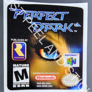 Może przedstawiać: Etykieta kasety z grą wideo Perfect Dark, wydanej przez Rareware na Nintendo 64. Etykieta przedstawia zbliżenie niebieskiego oka na ciemnym tle. Etykieta jest oceniona jako M dla dorosłych przez ESRB.