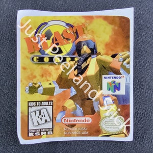 May include: A Nintendo 64 video game cartridge label for Blast Corps. The label features a yellow and orange background with a cartoon character wearing a gas mask and a yellow and orange suit. The label also includes the Nintendo 64 logo, the ESRB rating of "KA" for Kids to Adults, and the Nintendo Seal of Quality.