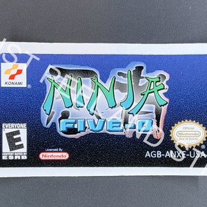 May include: A blue and green Game Boy Advance game cartridge label with the text "Ninja Five-O" and the Konami logo. The label also includes an ESRB rating of "Everyone" and an Official Nintendo Seal of Quality.