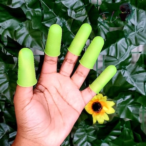 May include: A hand wearing five green silicone finger protectors. The protectors have a textured surface.
