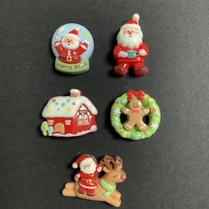 May include: A selection of festive Christmas figurines. The set features a Santa Claus in a snow globe, a standing Santa, a red house with a snowy roof, a gingerbread man in a wreath, and Santa riding a reindeer. The miniatures are brightly coloured and detailed.