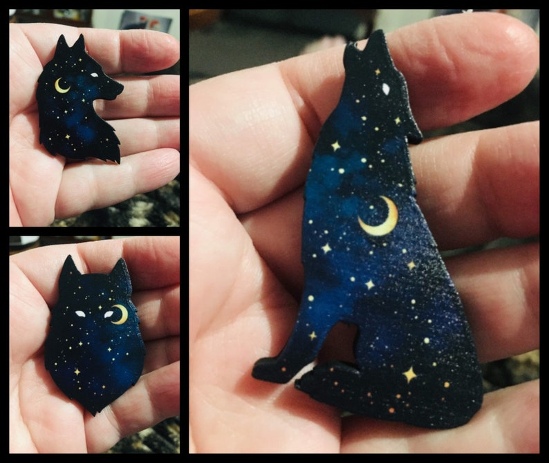 Pu&ograve; includere: Una silhouette di lupo in legno nero con una luna crescente e stelle dipinte su di essa. Il lupo sta ululando alla luna.