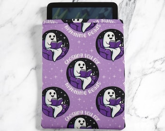 May include: A lavender tablet sleeve featuring a repeating pattern of a cartoon ghost reading a book while seated in a purple armchair. The text "Nighttime reads" and "Ghosting you for" are also included.
