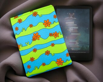 May include: A green, blue, and orange patterned Kindle case with a matching e-reader. The case features a wavy design with orange flowers. The e-reader displays a colorful illustration of a stack of books.
