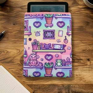 May include: A colorful, patterned e-reader case featuring a whimsical design of shelves with various cute objects. The case has a pink border and a rainbow background. The design includes potted plants, hearts, and other decorative elements.