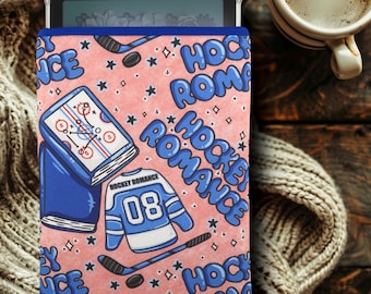May include: A pink and blue tablet case with a hockey theme. The case features a hockey jersey, hockey sticks, and the words "Hockey Romance".