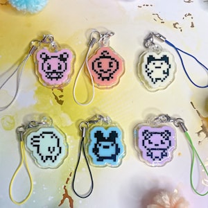 May include: Six colourful phone charms with different pixelated animal designs. Each charm is attached to a string.