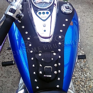Puede incluir: Un tanque de gasolina de motocicleta azul con una cubierta de tanque de cuero negro tachonada con una peque&ntilde;a bolsa y una hebilla. La cubierta del tanque tiene el texto "CHROME CRUISERS" impreso en ella.