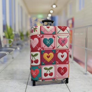Capa protetora para mala de viagem com estampa de corações e cerejas, em crochê com efeito patchwork.