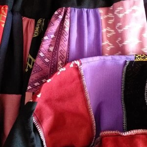 K&ouml;nnte beinhalten: Ein Patchwork-Rock aus verschiedenen Stoffen in Rot-, Lila-, Rosa- und Schwarzt&ouml;nen. Der Rock hat eine Vielzahl von Mustern, darunter geometrische Designs und Blumenmuster.