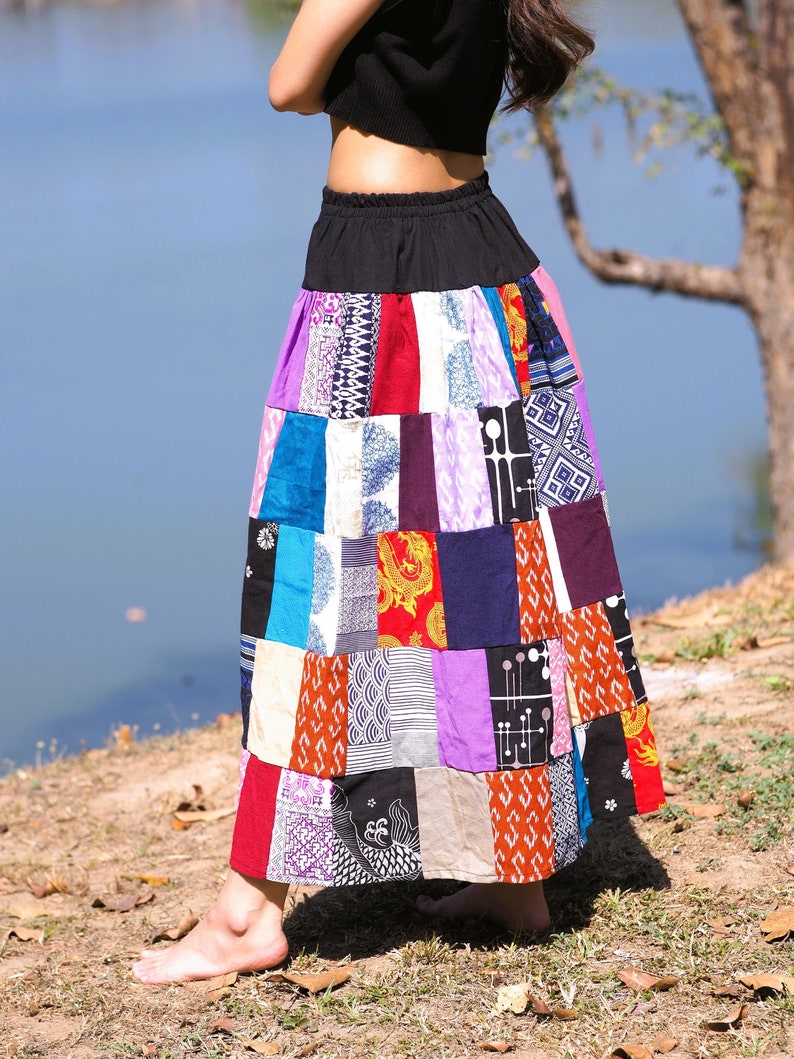 K&ouml;nnte beinhalten: Ein langer, bunter Patchworkrock mit einem schwarzen Bund. Der Rock besteht aus verschiedenen Stoffen und Mustern, darunter Blumen-, geometrische und Paisley-Muster. Der Rock wird von einer Person getragen, die auf einer grasbewachsenen Fl&auml;che steht.