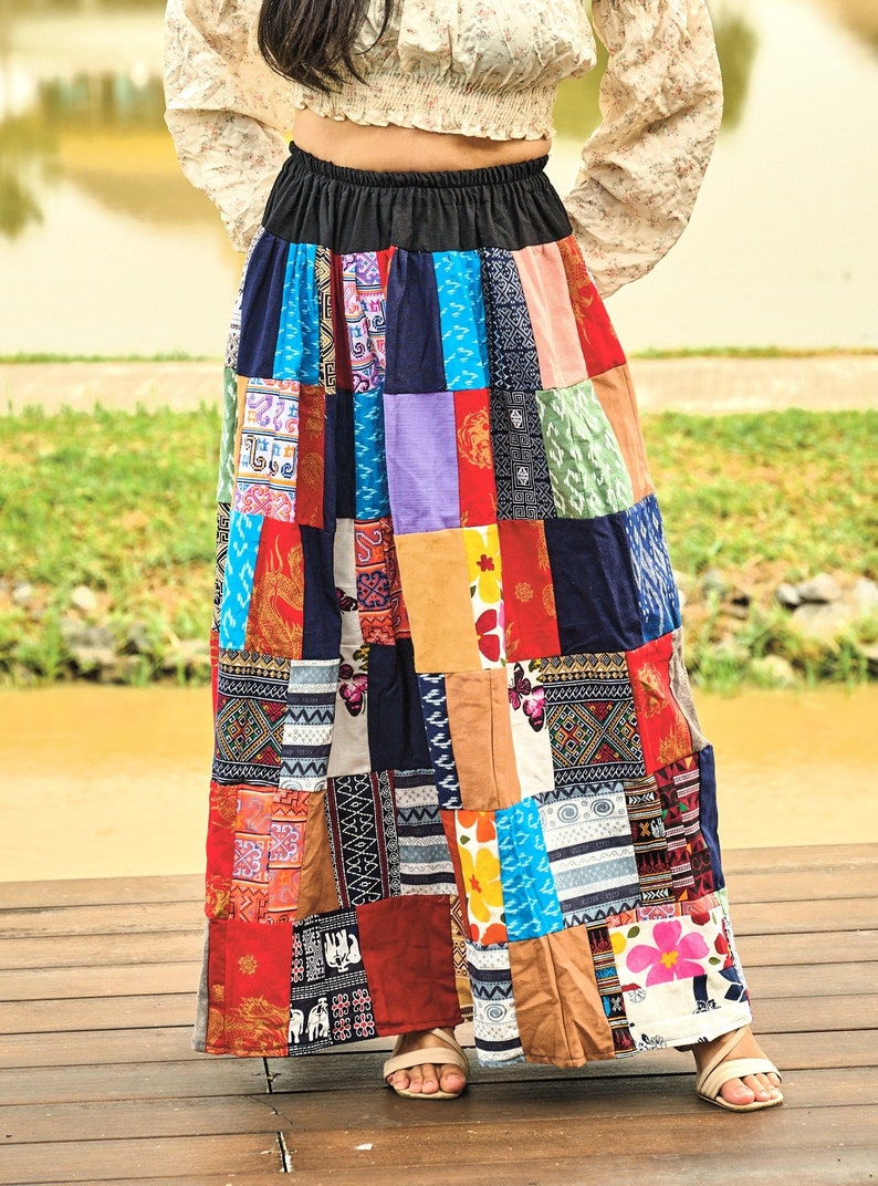 K&ouml;nnte beinhalten: Ein langer, bunter Patchworkrock mit einem schwarzen Bund. Der Rock besteht aus verschiedenen Stoffen mit unterschiedlichen Mustern und Farben, darunter Rot, Blau, Gr&uuml;n, Gelb und Lila.