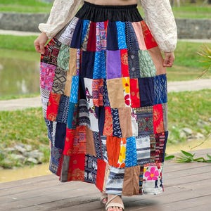 K&ouml;nnte beinhalten: Ein langer, bunter Patchworkrock mit einem schwarzen elastischen Bund. Der Rock besteht aus verschiedenen Stoffen mit unterschiedlichen Mustern, darunter Blumen-, geometrische und Paisley-Muster.