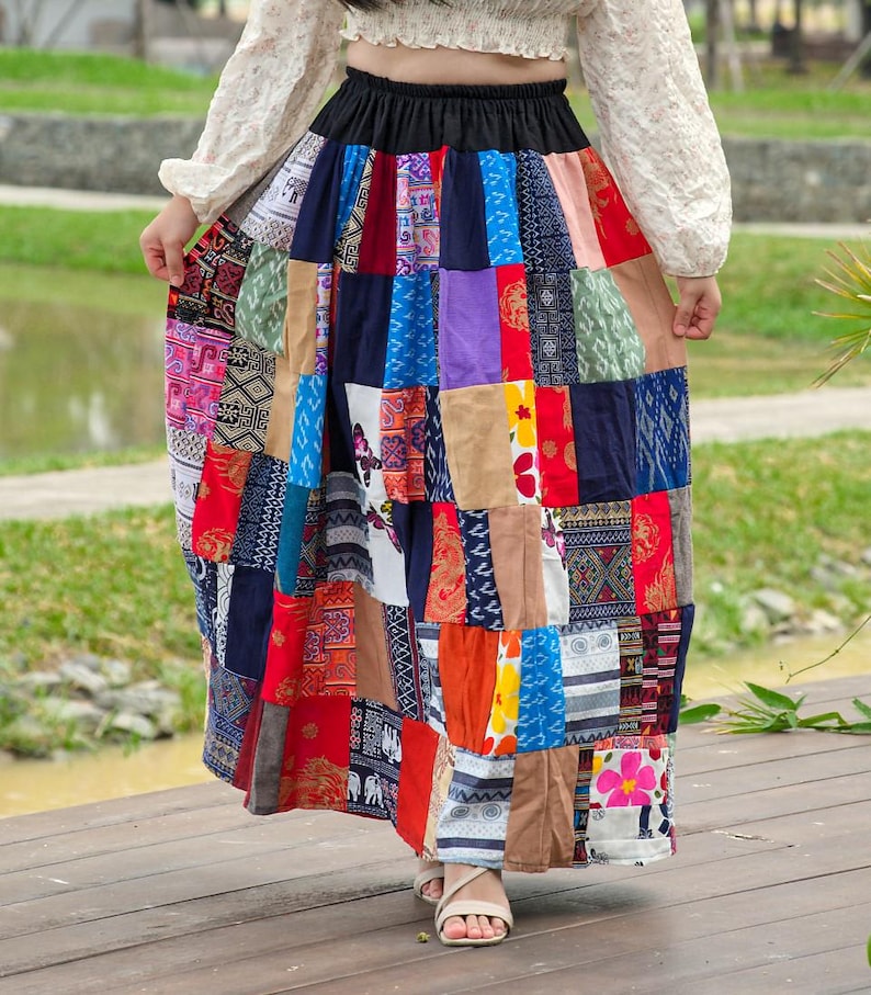 K&ouml;nnte beinhalten: Ein langer, bunter Patchworkrock mit einem schwarzen elastischen Bund. Der Rock besteht aus verschiedenen Stoffen mit unterschiedlichen Mustern, darunter Blumen-, geometrische und Paisley-Muster.