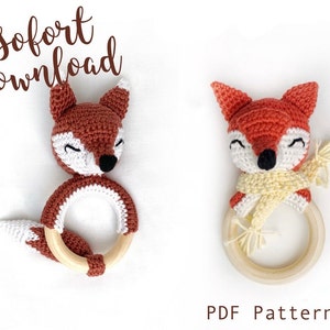 Puede incluir: Dos juguetes de sonajero de zorro de crochet con anillos de madera. Un zorro lleva una bufanda amarilla. El texto "PDF Pattern" está en la parte inferior de la imagen.