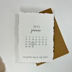 K&ouml;nnte beinhalten: Eine wei&szlig;e Karte mit einem handgeschriebenen Kalender f&uuml;r Januar 2025. Der 24. ist mit einem Herzen umkreist. Der Text "wir freuen uns so auf dich!" steht unten auf der Karte.