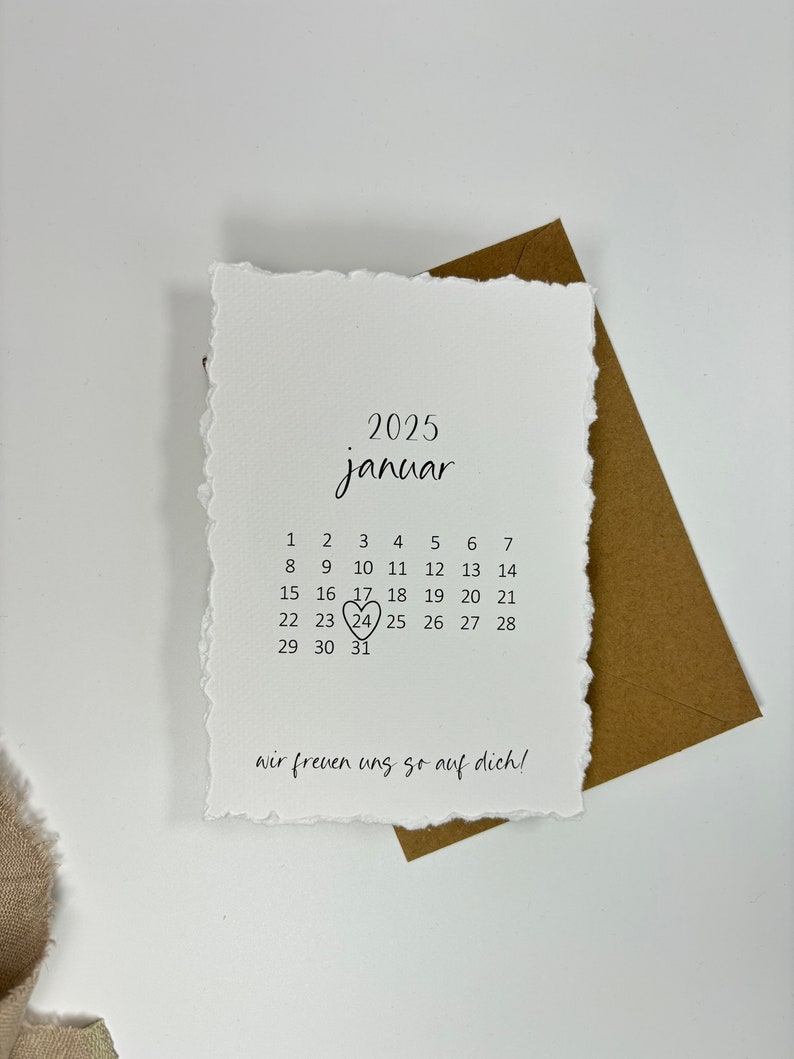 K&ouml;nnte beinhalten: Eine wei&szlig;e Karte mit einem handgeschriebenen Kalender f&uuml;r Januar 2025. Der 24. ist mit einem Herzen umkreist. Der Text "wir freuen uns so auf dich!" steht unten auf der Karte.