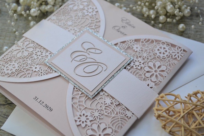 Laser cut wedding invitation in blush pink colour. Laser cut initials added at the front on the silver glittery background.