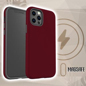 May include: A burgundy phone case with a black screen, next to a phone. The case has a MagSafe logo. The phone case is designed to protect the phone from damage.