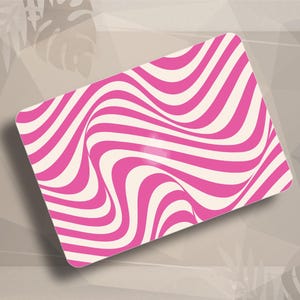 May include: A rectangular mouse pad featuring a vibrant pink and off-white wavy striped pattern. The design consists of repeating, fluid, curved lines that create a sense of movement across the entire surface of the flat, rectangular object.