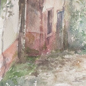 May include: Watercolor painting of a building facade with a weathered appearance. The building is painted in muted tones of beige, brown, and red, with hints of green foliage. Two windows are visible, and the overall style is impressionistic.