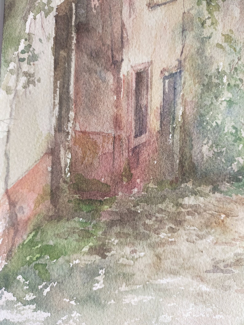 May include: Watercolor painting of a building facade with a weathered appearance. The building is painted in muted tones of beige, brown, and red, with hints of green foliage. Two windows are visible, and the overall style is impressionistic.