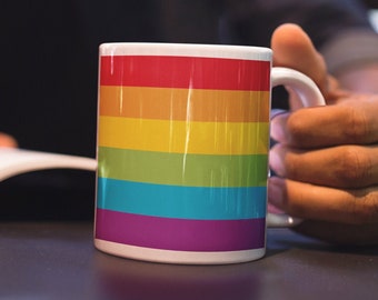 May include: A white ceramic mug with a rainbow design. The mug has six stripes of red, orange, yellow, green, blue, and purple.