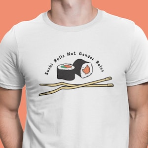 May include: White t-shirt with a graphic of two sushi rolls and chopsticks. The text "Sushi Rolls Not Gender Roles" is printed on the shirt.