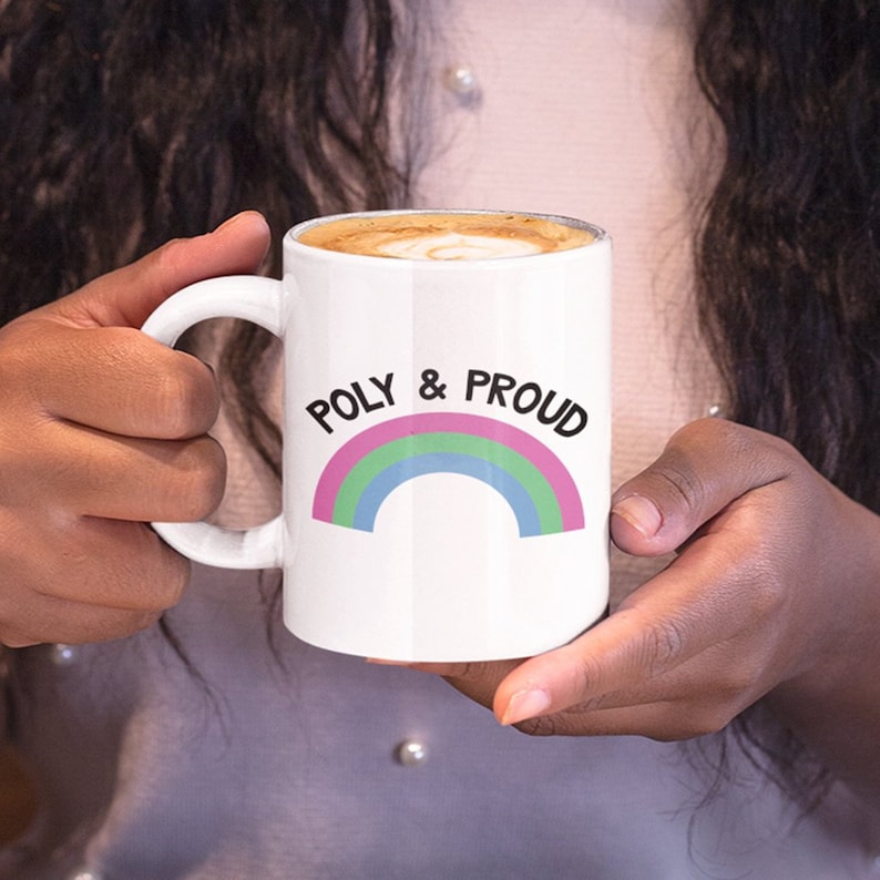 May include: White ceramic mug with a rainbow design and the text "POLY & PROUD" in black lettering.