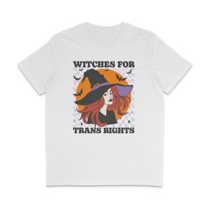 White crew neck shirt featuring the slogan Witches for Trans Rights with an illustrated graphic of a witch with bats flying around her hat