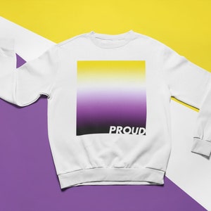 May include: White sweatshirt with a yellow, white, purple and black gradient square print and the word "PROUD" printed below the square.