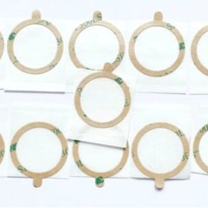 May include: Ten round, adhesive-backed, beige-colored circles with a green adhesive backing. The circles are on white paper.