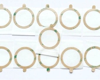 May include: Ten round, adhesive-backed, beige-colored circles with a green adhesive backing. The circles are on white paper.