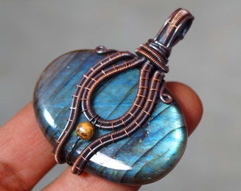 Peut inclure: Un pendentif en fil de cuivre enroulé avec une pierre précieuse de labradorite bleue et verte avec un accent de perle dorée.