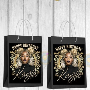 May include: Three black gift bags with white handles. Each bag features a portrait of a woman with blonde hair and the text "Happy Birthday Kayla" in gold lettering. The background includes a leopard print design.