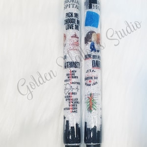 May include: Two white glitter pens with black ink. One pen has the text "Grey Sloan Memorial Hospital" and "Pick me, Choose me, Love me" on it. The other pen has the text "Grey's Anatomy" and "You're my person" on it.