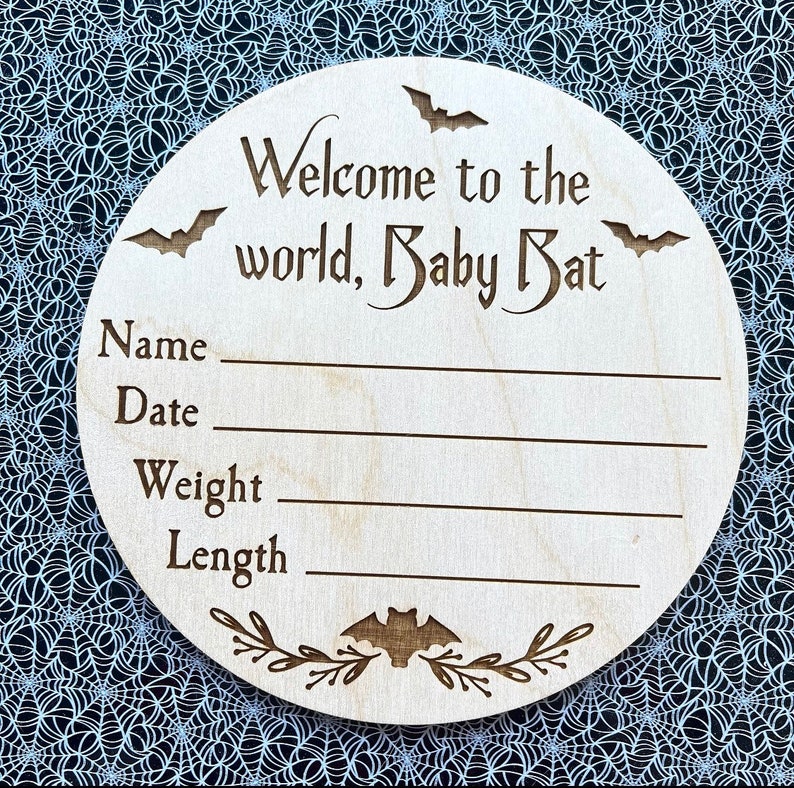 May include: A wooden baby announcement plaque with the text "Welcome to the world, Baby Bat". The plaque has spaces to fill in the baby's name, date, weight, and length.
