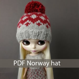 May include: A gray and red knitted hat with a pom-pom on top. The hat has a traditional Norwegian pattern. The hat is being worn by a doll with blonde hair. The text "PDF Norway hat" is at the bottom of the image.