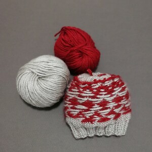 May include: Two balls of yarn, one gray and one red, and a knitted hat with a red and gray pattern.