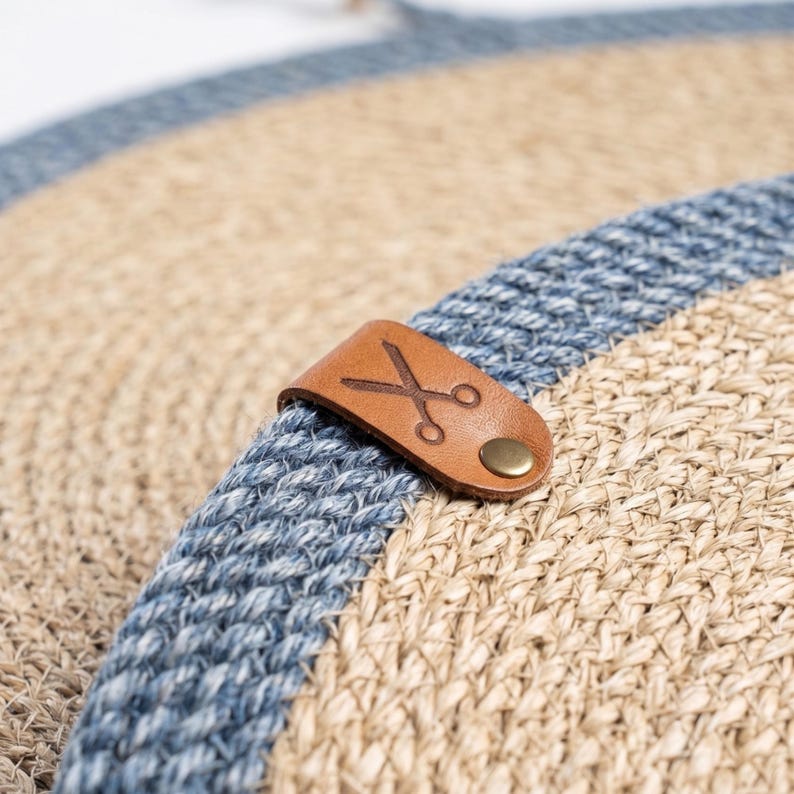 Close-up of a denim blue stripe on an oval jute placemat over a round woven mat, showing the fiber texture.