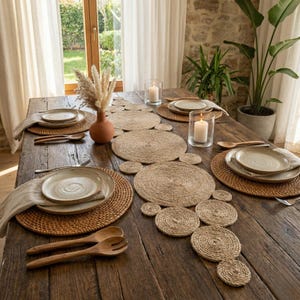 Stone walled dining room with a jute circle runner on a rustic table, rattan placemats, pillar candles and a terracotta vase of pampas