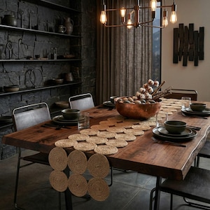 May include: A rustic dining table set for a meal. The table is made of dark wood and has a natural edge. It is set with dark green plates, glasses, and a woven jute placemat. A copper bowl holds decorative stones.